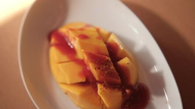 Plate of chopped mango with Mexican chamoy sauce and blurry background