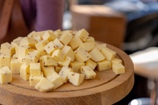 Selective focus of diced cheese on the wooden plank, Blocks of young cheese on chopping wood display on the market in Netherlands, Produced exclusively from cow's' milk, Dutch farms.