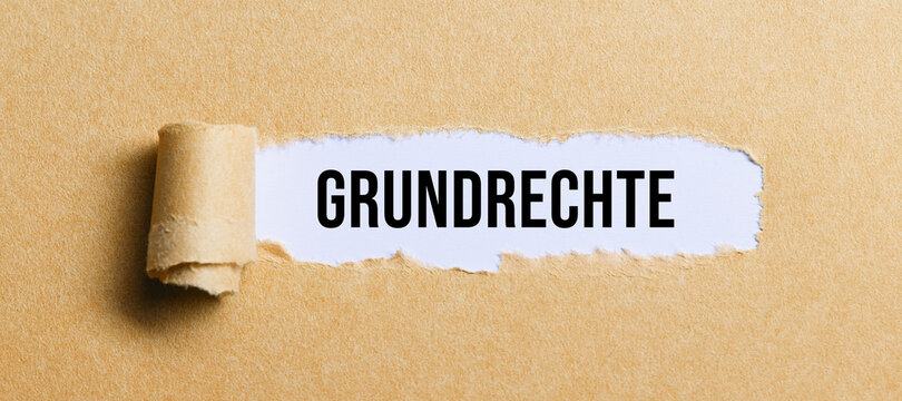 torn paper revealing the message BASIC RIGHTS in German on white background