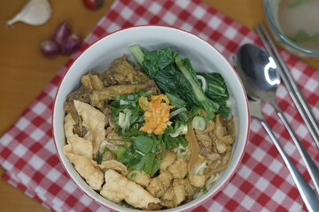 mie ayam or chicken noodle and wooden chopsticks indonesian food with toped chicken filet and meatball on the wood table front angle with property