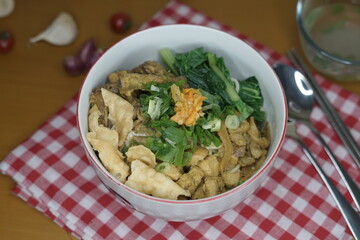 mie ayam or chicken noodle and wooden chopsticks indonesian food with toped chicken filet and meatball on the wood table front angle with property