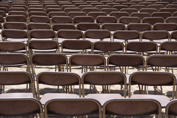 Full frame view of rows of outdoor folding chairs seen from the backside - obrazy, fototapety, plakaty