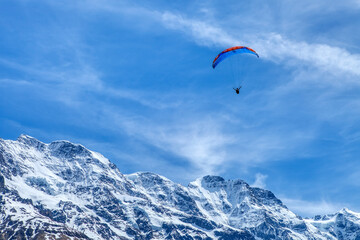 Fototapeta na wymiar Paraglider in the blue sky. The sportsman flying on a paraglider. Leisure sports activity in holiday