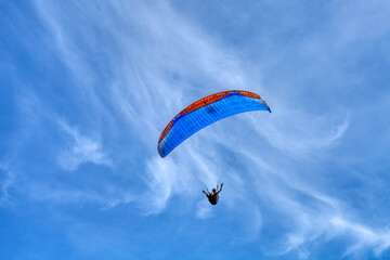 Paraglider in the blue sky. The sportsman flying on a paraglider. Leisure sports activity in holiday