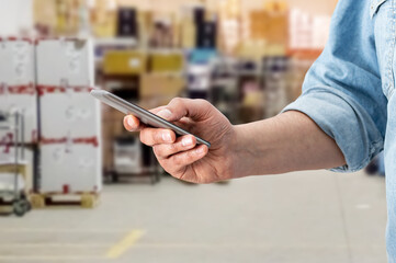 Warehouse factory contact holding mobile cell phone. Man hand holding cell phone checking factory warehouse management, person smart logistic mobile industry using phone and internet control business.