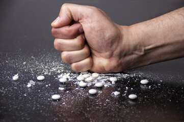 hand crushing white pills