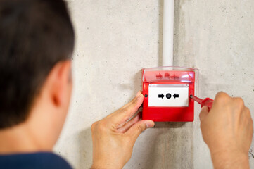 A back view of electrician installing fire alarm system - obrazy, fototapety, plakaty