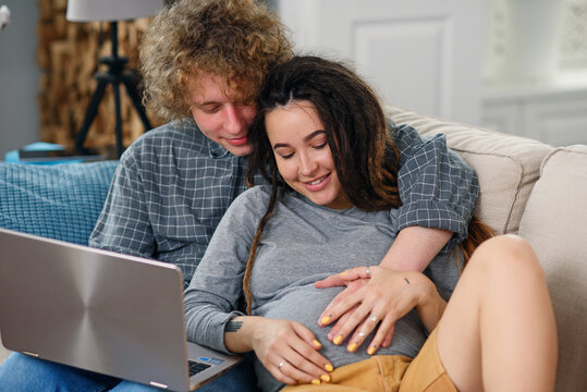 Young pregnant couple expecting a baby and looking to their family photo book.