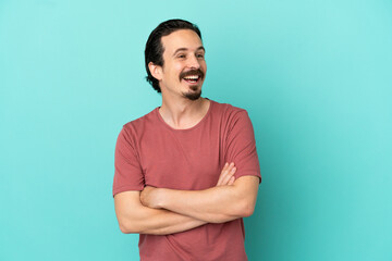 Young caucasian man isolated on blue background happy and smiling
