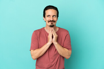 Young caucasian man isolated on blue background scheming something