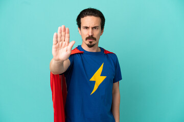 Super Hero caucasian man isolated on blue background making stop gesture