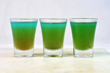 three drink dose of absinthe, tequila and vodka with lemon in the glass cup on the table, horizontal image with blurred background