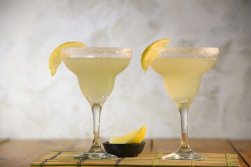 two shots of cozumel, margarita, tequila drink with lemon in the glass on the table, horizontal image with blurred background