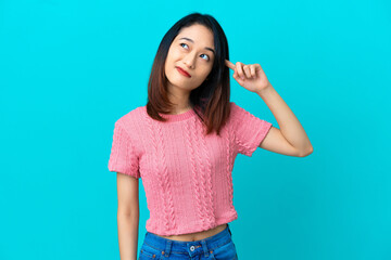 Fototapeta premium Young Vietnamese woman isolated on blue background making the gesture of madness putting finger on the head