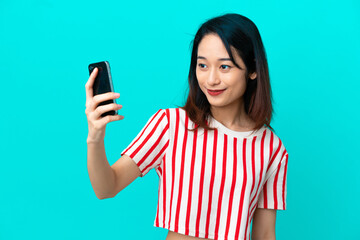 Young Vietnamese woman isolated on blue background making a selfie