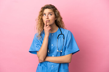 Young surgeon doctor woman isolated on pink background having doubts while looking up