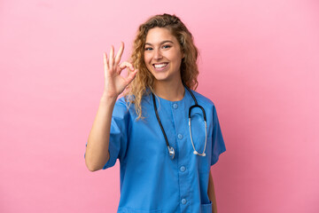 Young surgeon doctor woman isolated on pink background showing ok sign with fingers