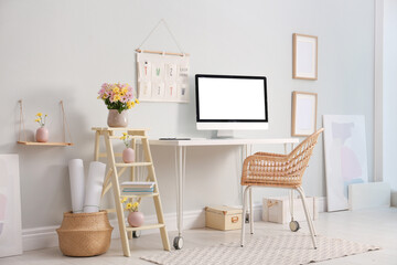 Comfortable workplace with modern computer and flowers in room. Interior design