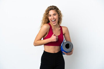 Young sport blonde woman going to yoga classes while holding a mat isolated on white background giving a thumbs up gesture