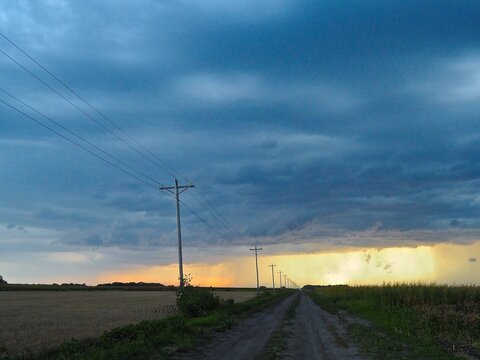 Kansas dirt road leads to sunset thunderstorm. 