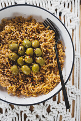 vegan ginger noodles with chilli flakes and coriander seeds topped with olives and breadcrumbs, healthy plant-based food