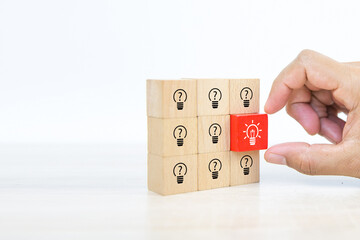 Close up hand choosing light bulb or lamp icons on cube wooden toy blocks concepts human resources for business leadership and creativity.