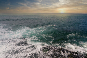 Sunset or sunrise on Pacific ocean from rocky shore