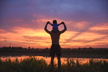 Fototapeta premium silhouette of father and son at sunset happy life