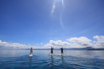 people paddling sup standup paddle boards in calm blue waters. Philippines