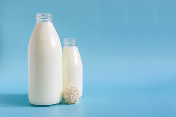 Two glass bottles of milk on a bright blue background. One liter and 0.5 liters of milk in glass bottles on a colored background space for text
