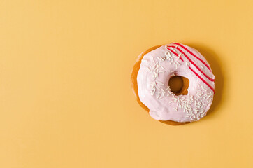 A fresh donut with pink icing on a bright yellow background. Pink donut on a colored background close-up copy space	