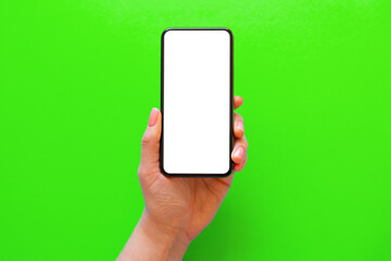 Person holding mobile phone with empty white screen on green background