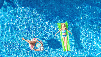 Children in swimming pool aerial drone view from above, happy kids swim on inflatable ring donut...