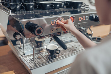 Young woman barista using modern coffee machine in cafeteria
