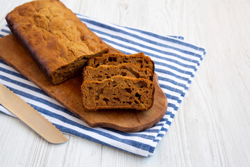 Homemade Pumpkin Loaf Bread on a rustic wooden board on a white wooden surface, side view.