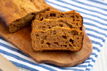 Fototapeta na wymiar Homemade Pumpkin Loaf Bread on a rustic wooden board on a white wooden surface, side view. Close-up.
