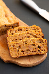 Homemade Pumpkin Loaf Bread on a rustic wooden board on a black background, low angle view.