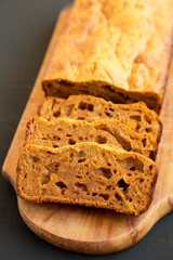 Homemade Pumpkin Loaf Bread on a rustic wooden board on a black background, side view.