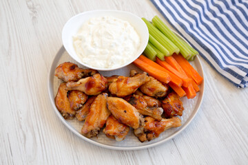 Homemade Chicken Wings with Blue Cheese Dip on a white wooden table, side view.