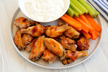 Homemade Chicken Wings with Blue Cheese Dip on a white wooden surface, low angle view. Close-up.