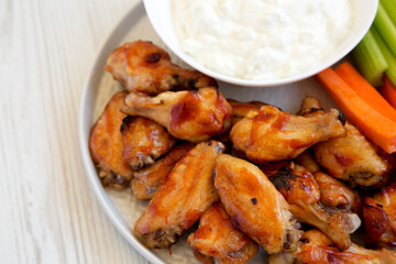 Homemade Chicken Wings with Blue Cheese Dip on a plate on a white wooden background, close-up.