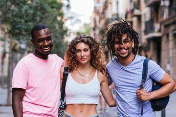 horizontal portrait of three friends in the streets of Barcelona. One caucasian woman, a latin american man and an afro american man