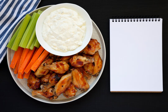 Homemade Chicken Wings With Blue Cheese Dip, Blank Notepad On A Black Background, Top View. Flat Lay, Overhead, From Above. Copy Space.