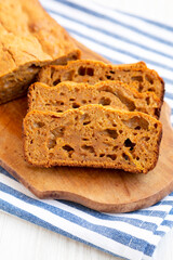 Homemade Pumpkin Loaf Bread on a rustic wooden board on a white wooden background, side view.