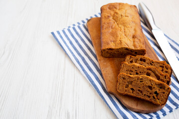 Homemade Pumpkin Loaf Bread on a rustic wooden board on a white wooden surface, side view. Space for text.