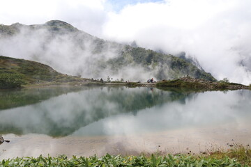 八方池。谷から湧き上がる雲にかすむ背景の山が、水に映る。

