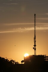 Construction crane silhouetted at sunrise.