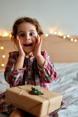 Happy laughing child girl with Christmas gift at home. Christmas surprise. Christmas holidays concept, New Years Eve.