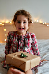 
Happy laughing child girl with Christmas gift at home. Christmas surprise. Christmas holidays concept, New Years Eve
