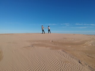 Fototapeta na wymiar Couple Walking Across Sand Dunes Australia